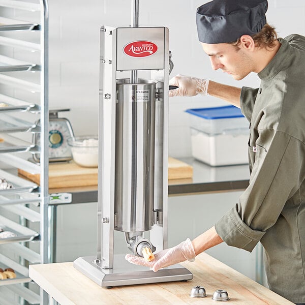 A man wearing gloves uses a silver Avantco vertical churro stuffer to fill churro dough.