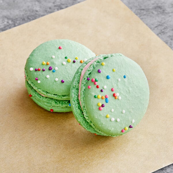 Two green Macaron Centrale macarons with sprinkles.