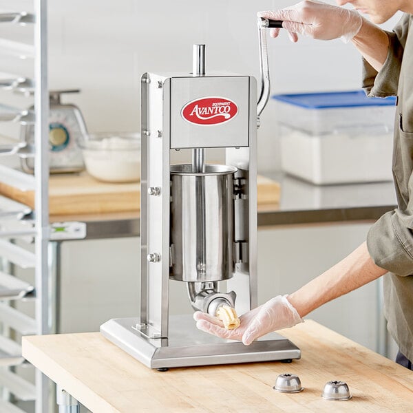 A woman in gloves using an Avantco stainless steel churro stuffer to make dough.