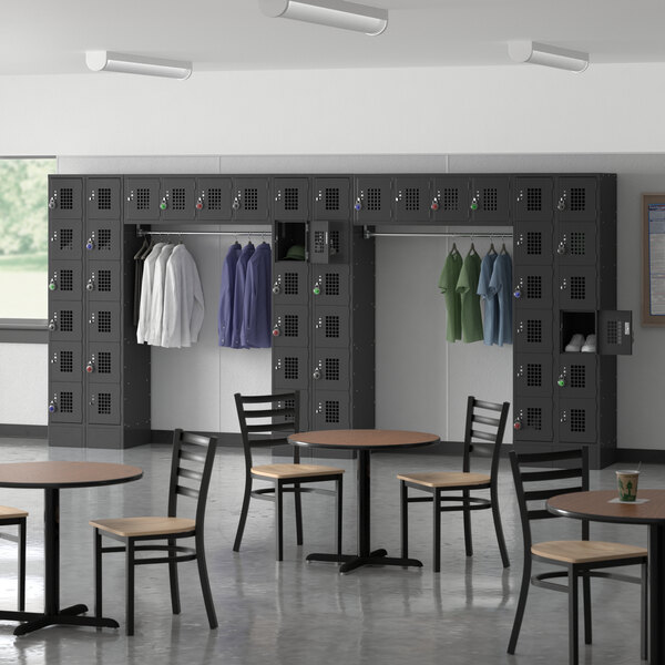 A Regency black 6 tier locker with garment rack in a room with tables and chairs.