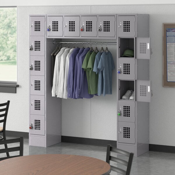 A Regency gray locker room with 16 compartments and a garment rack with clothes on it.