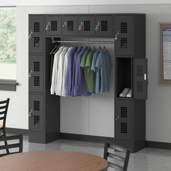 A room with a black Regency locker with clothes hanging on it and a table and chairs.