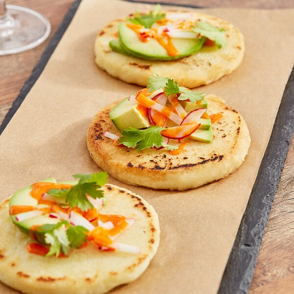 Three small flatbreads made with Goya Pre-Cooked White Corn Meal on a tray.