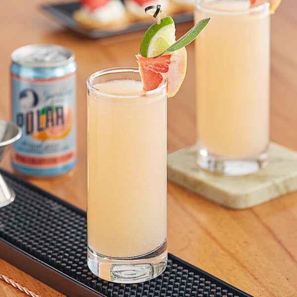 A tray with two glasses of Polar Pink Grapefruit juice on a black rubber mat.