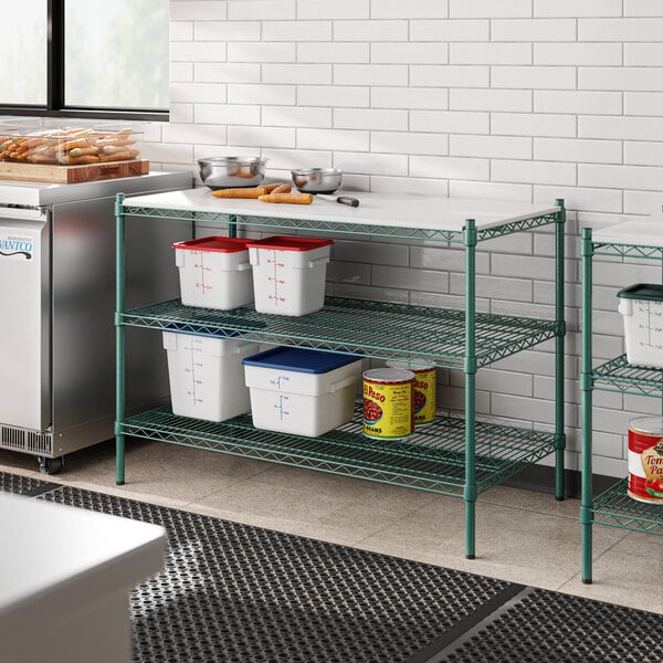 A kitchen with a green metal Regency shelf next to a white table.