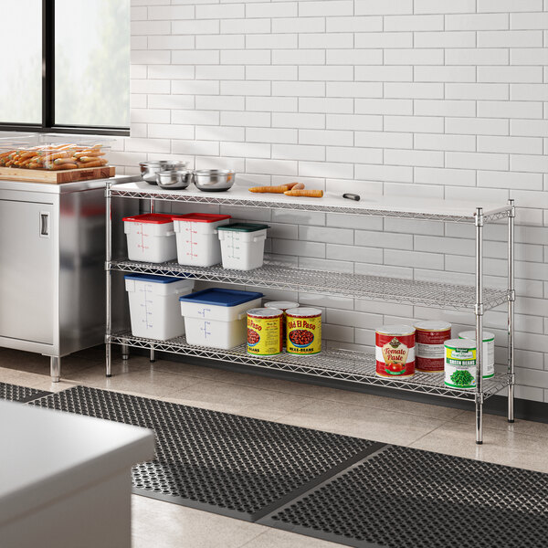 A Regency metal shelving unit on a stainless steel counter in a professional kitchen.