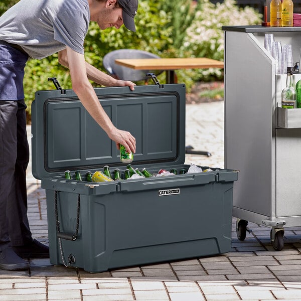 A man putting a can into a CaterGator outdoor cooler.