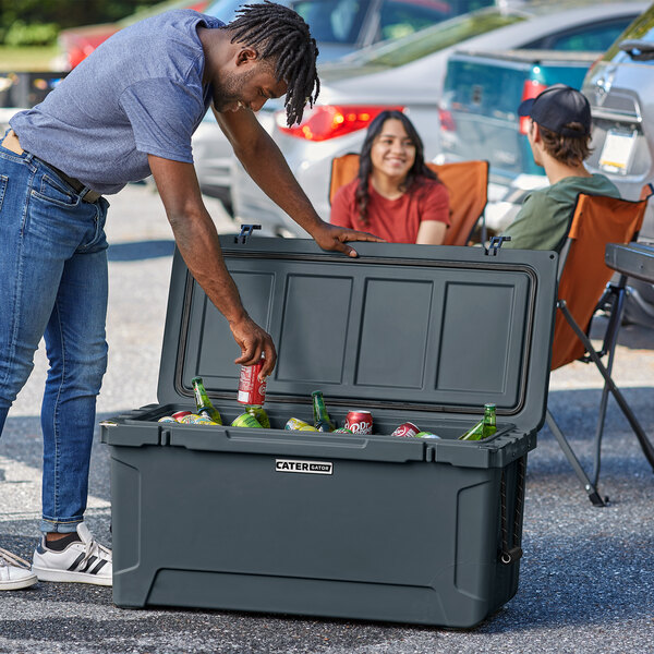 A man wearing a hat putting a can in a CaterGator outdoor cooler.