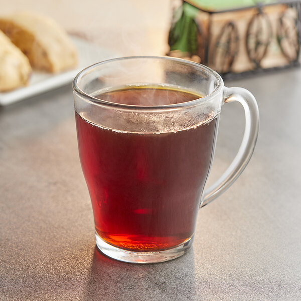 A glass mug filled with brown liquid on a table.