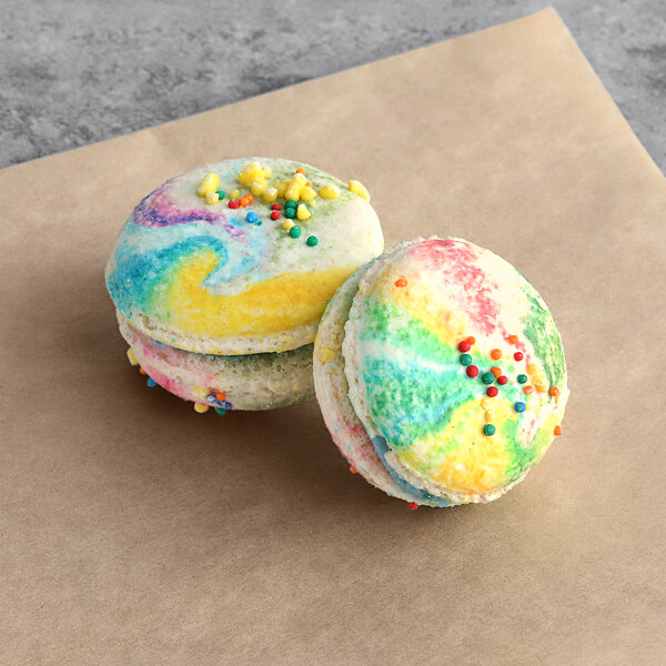 A stack of multicolored Macaron Centrale unicorn macarons with sprinkles on top.