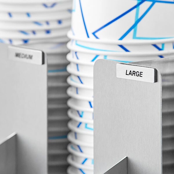 A stack of paper cups with a white rectangular label with a black border on them.