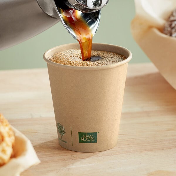 A cup of coffee being poured into a New Roots Kraft paper hot cup.