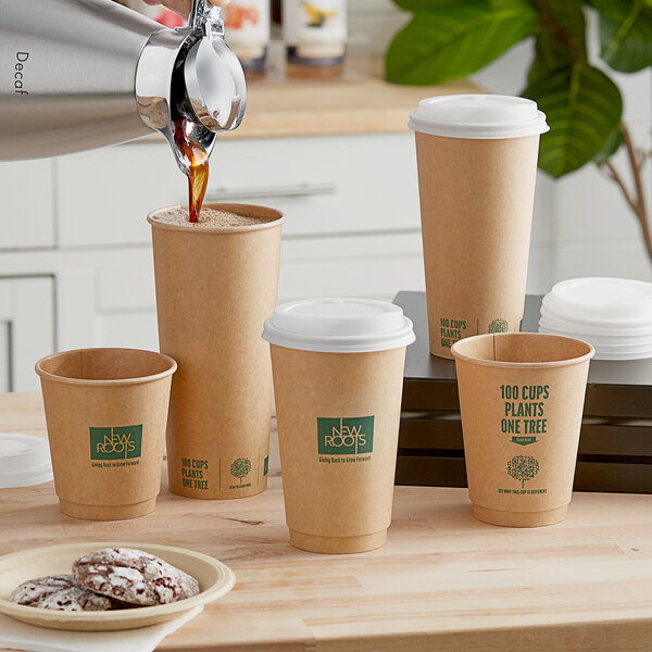 A person pouring coffee into a brown New Roots paper cup with green text.