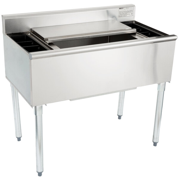 An Eagle Group underbar ice bin with a stainless steel lid over a large stainless steel container with 7 circuits.