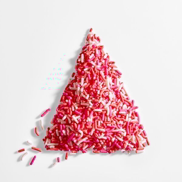 A triangular pile of red, pink, and white Valentine's Day sprinkles on a white background.