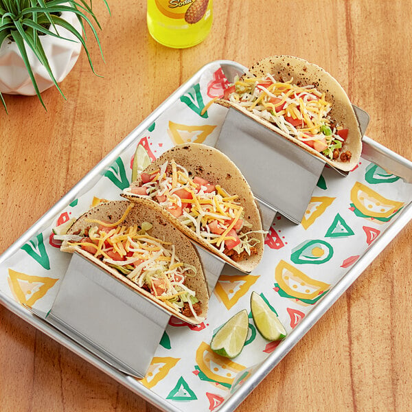 A stainless steel taco holder with 5 compartments holding 3 tacos on a table.