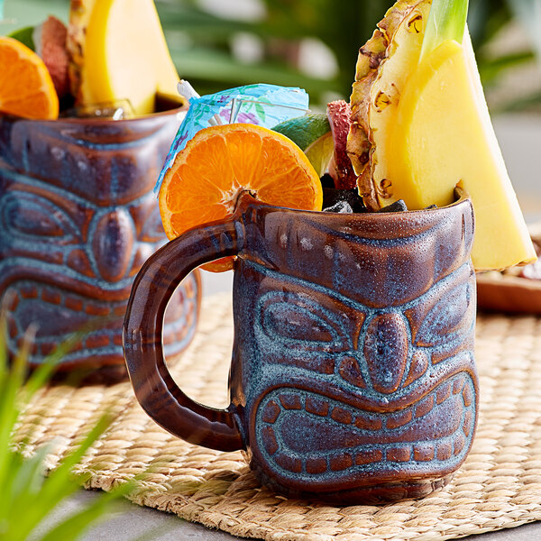 Two Libbey brown tiki mugs filled with fruit slices.
