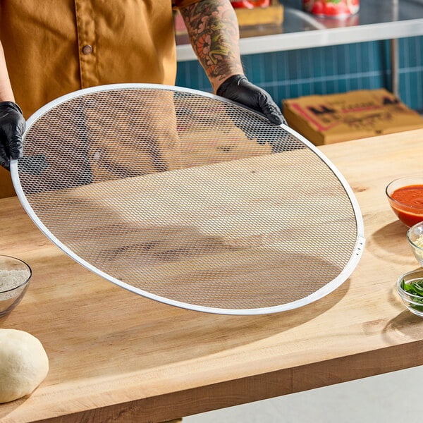 A large, round, heavy-duty expanded aluminum pizza screen.