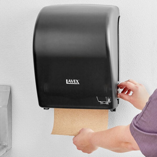 A person using a Lavex Translucent Black paper towel dispenser.