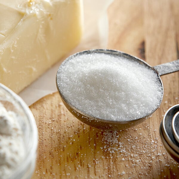 A spoon with Extra Fine Granulated Cane Sugar and butter on a wood surface.