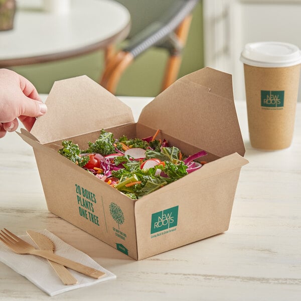 A New Roots Kraft compostable take-out container of salad on a table.