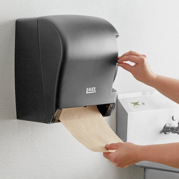A person using a Lavex black lever activated paper towel dispenser.
