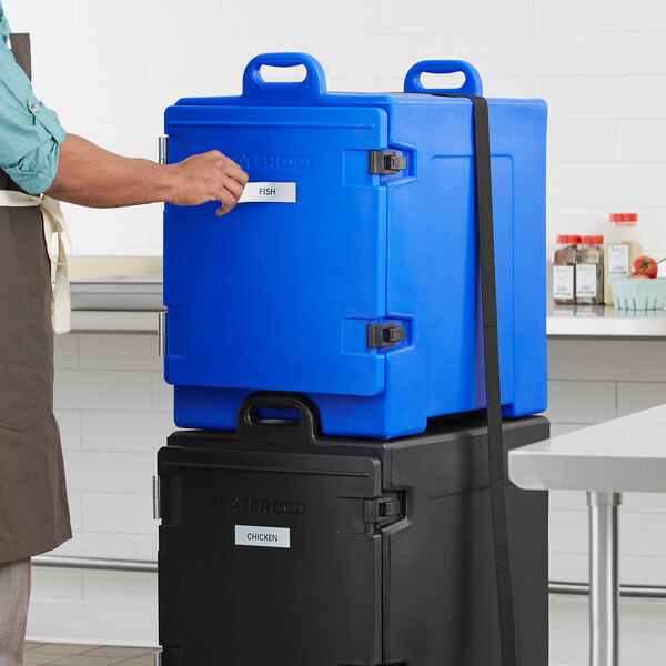 A man using a blue CaterGator front-loading pan carrier to hold a blue container.