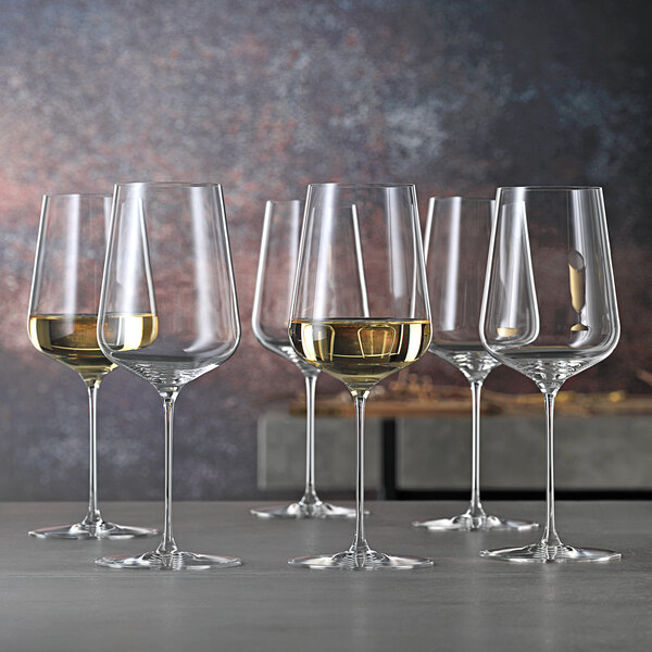A group of Spiegelau wine glasses filled with white wine.