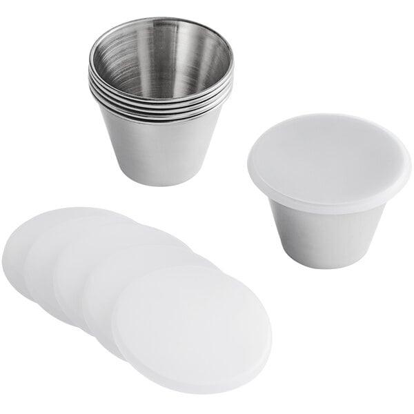 A white container with a stack of Tablecraft stainless steel round sauce cups and lids.