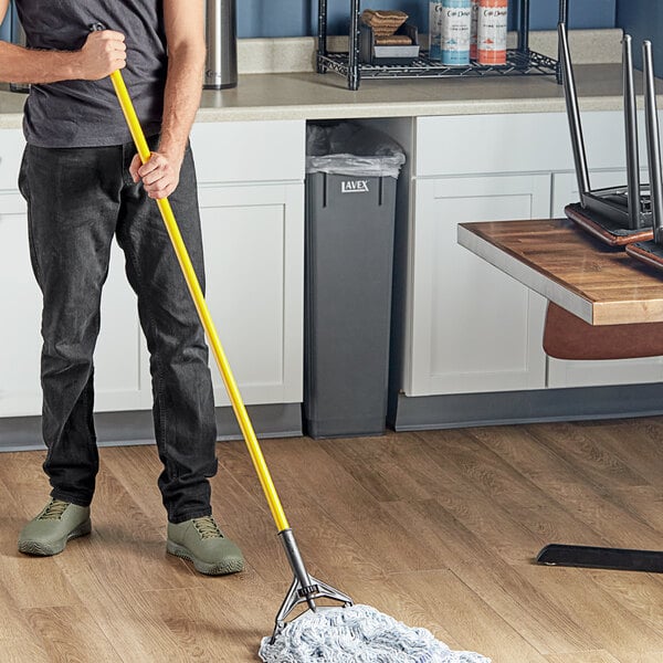 A person using a Lavex metal mop handle to clean the floor in a professional kitchen.