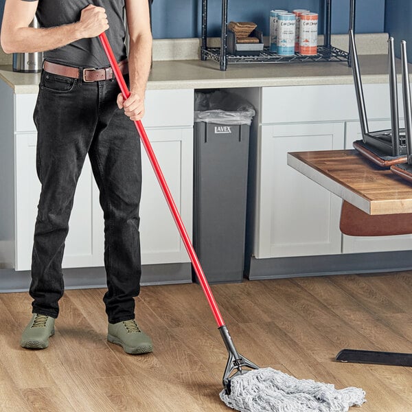 A man using a Lavex red mop handle to clean the floor.