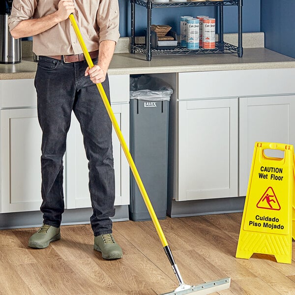 A man using a Lavex yellow metal handle for a mop.