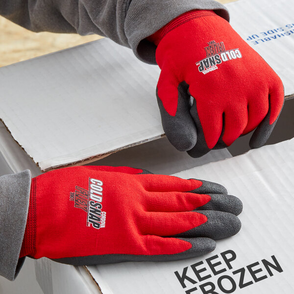 A person wearing red Cordova Cold Snap thermal gloves with black foam PVC palms.