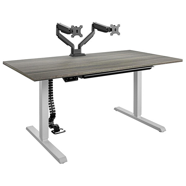 A Bridgeport gray computer desk with dual monitor arms on it.