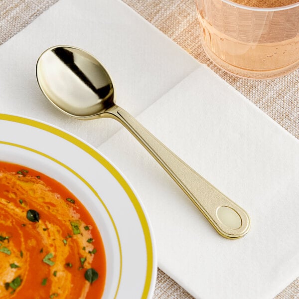 A Visions heavy weight gold plastic soup spoon in a bowl of soup.