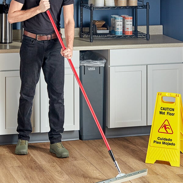 A man holding a Lavex red fiberglass broom handle.