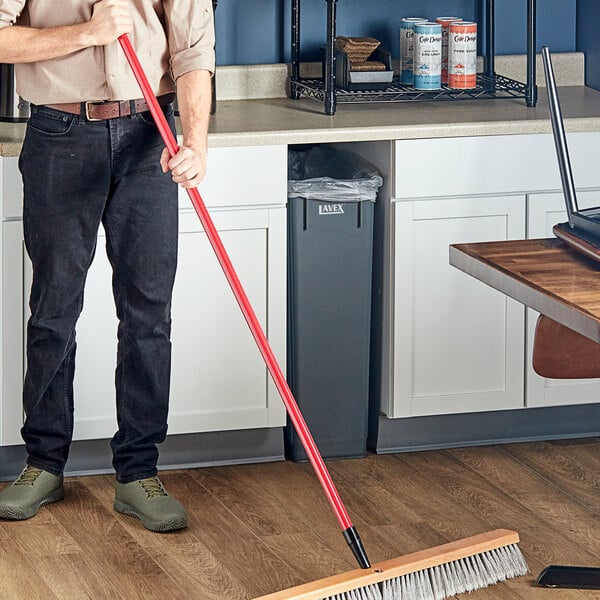 A man holding a Lavex metal broom handle.