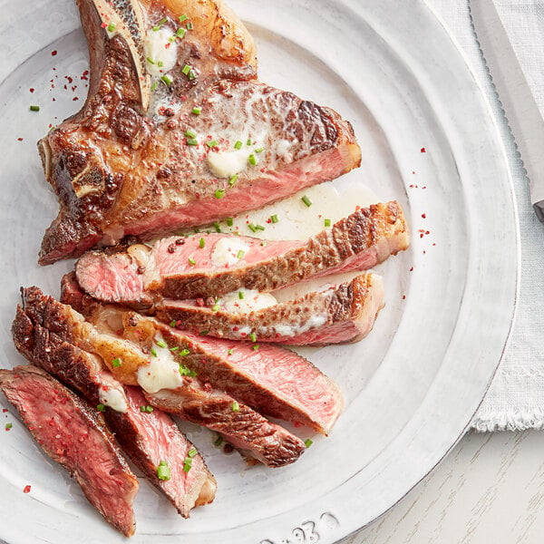 A plate of steak with Urbani White Truffle Butter and green onions on a white surface.