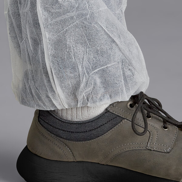 A person wearing white Malt Impact PolyLite coveralls over shoes.