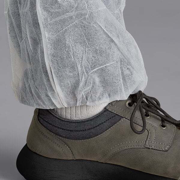 A person wearing white Malt Impact coveralls with shoe covers over their shoes.