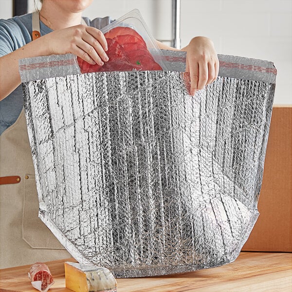 A woman holding a Lavex Pro insulated box liner filled with food.