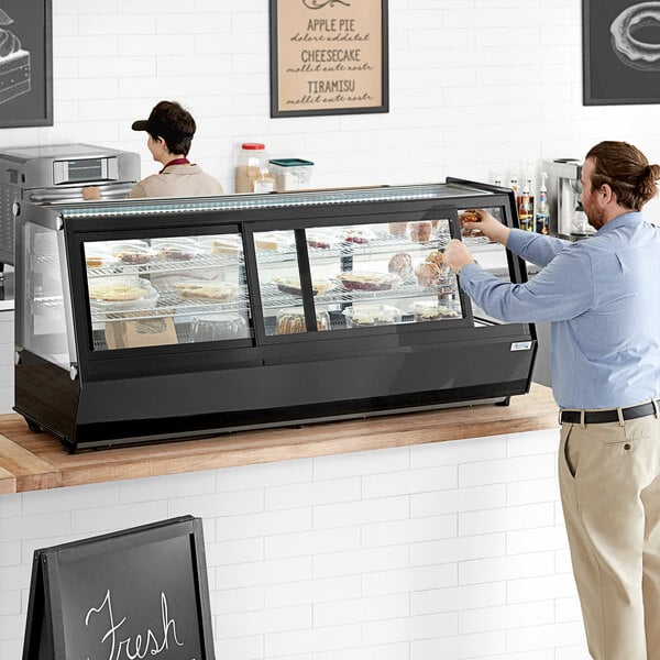 A man standing at a counter with food in a display case.