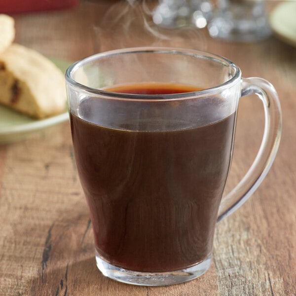 A glass cup of Ellis Mezzaroma Blueberry Muffin coffee on a plate of cookies.