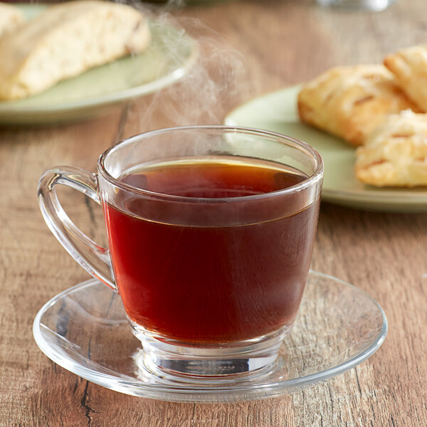 A glass cup of Ellis Mezzaroma French Caramel Creme coffee on a plate with pastries.