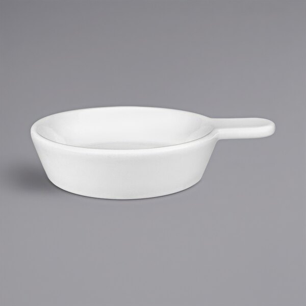 A white porcelain sampling skillet with a handle.