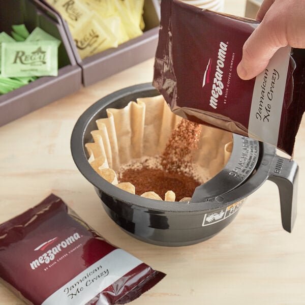 A person pouring Ellis Mezzaroma Jamaican Me Crazy coffee into a filter.