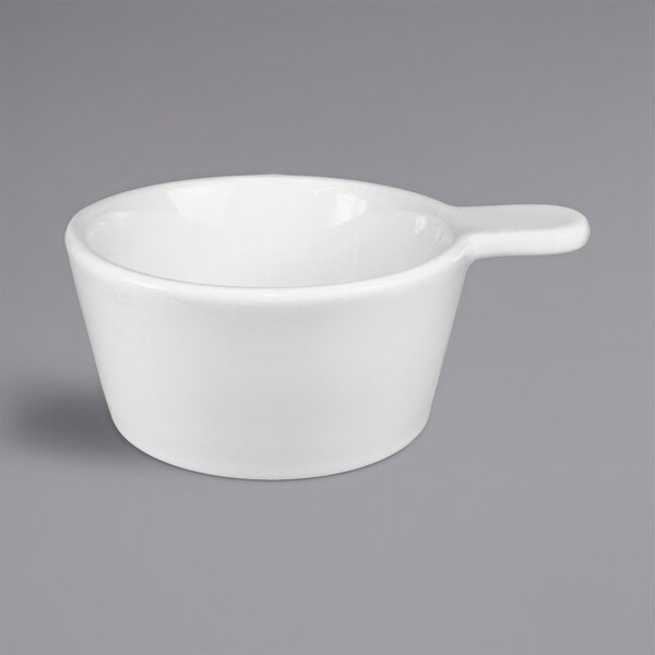 A white International Tableware porcelain sampling bowl with a handle.