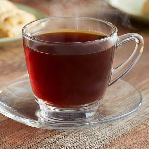 A box of Ellis Colombian coffee single serve cups on a saucer with a glass cup of coffee.
