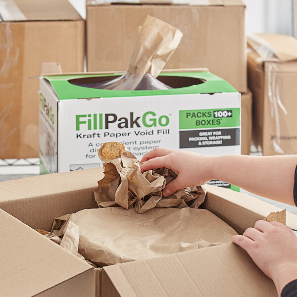A hand using Ranpak Fanfold paper to fill a box.