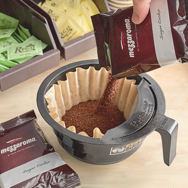 A hand pouring Ellis Mezzaroma Sugar Cookie coffee into a coffee filter.